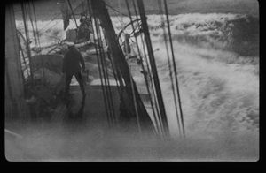 Image of Rough seas wash over deck. Man on deck